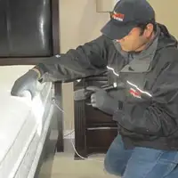 Bed bug inspection technician checking a mattress and bed frame for signs of infestation in Raleigh, NC