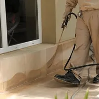 General pest control technician spraying exterior perimeter around a home in Raleigh, NC