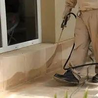 General pest control technician spraying exterior perimeter around a home in Raleigh, NC