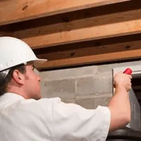 Termite inspection technician checking a basement wall and framing for termite activity in Raleigh, NC