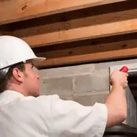 Termite inspection technician checking a basement wall and framing for termite activity in Raleigh, NC